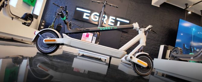 Der Egret Ey! 3 E-Scooter in einer urbanen Umgebung, zeigt seine schlanke Bauweise und innovative Federung. Perfekt für den täglichen Gebrauch in der Stadt.